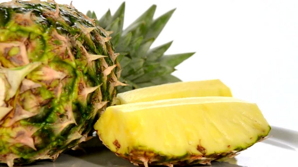 Pineapple laying on a cutting board with white background